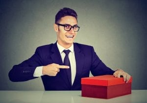a salesman in a black tie point excitedly at a red box