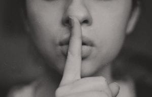 a woman holding her finger to her lips in the "shhh" gesture