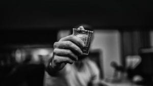 a black and white photo of a person holding out a one dollar bill