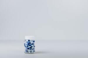 a jar of blue pills on a white background