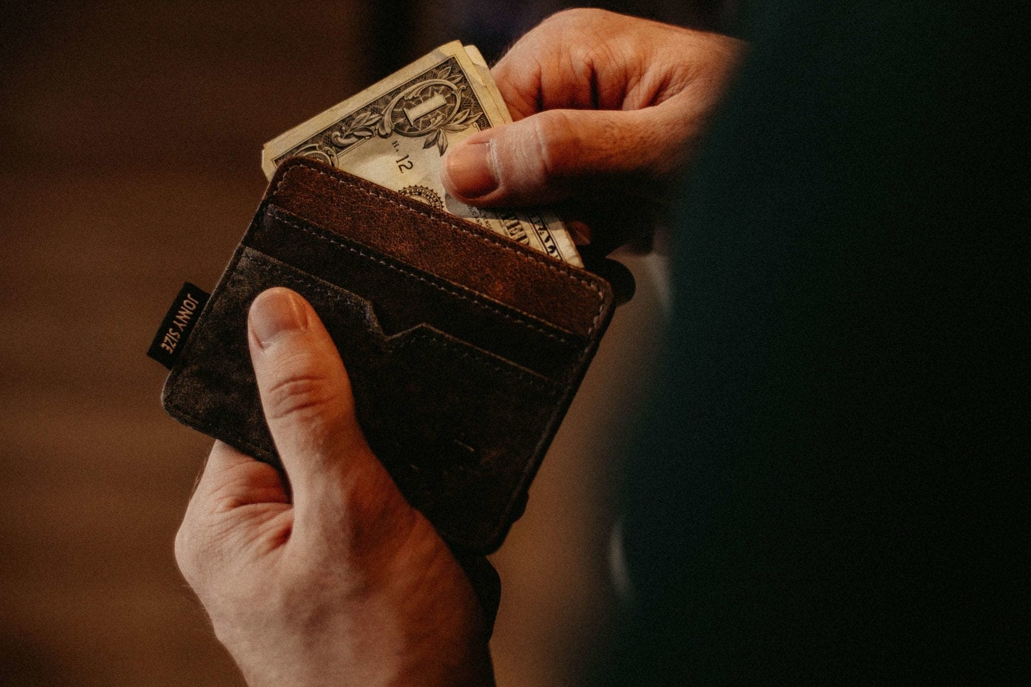 a closeup photo of a person pulling dollar bills from a wallet