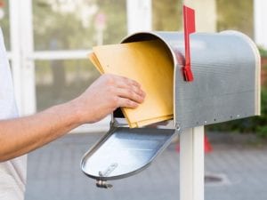 large envelopes being placed in a mailbox