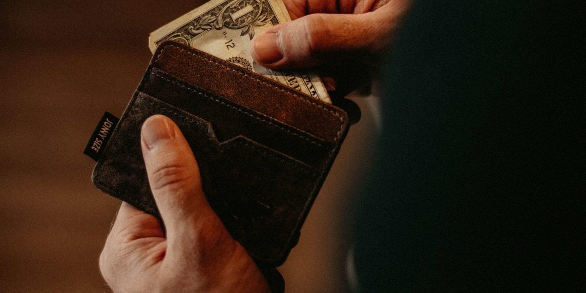 a closeup photo of a person pulling dollar bills from a wallet