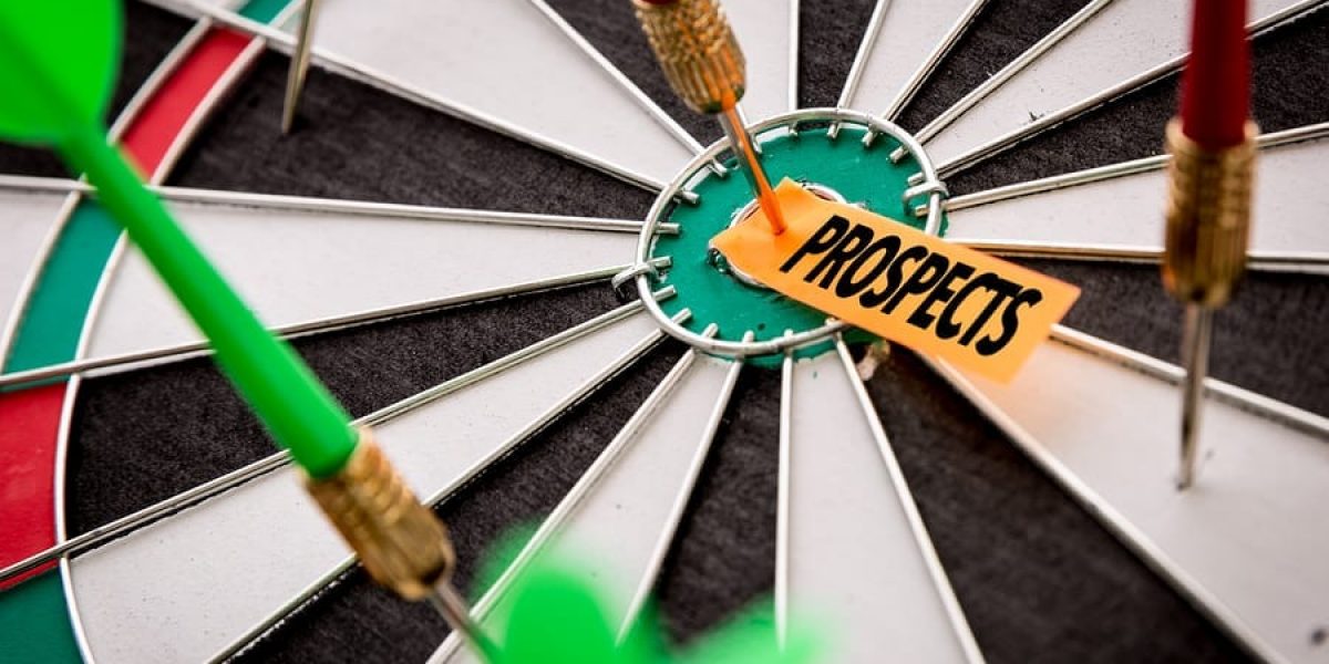 a closeup photo of a dart board with several darts stuck in, and one dart in the bullseye, pinning a piece of paper labeled "Prospects" to the bullseye