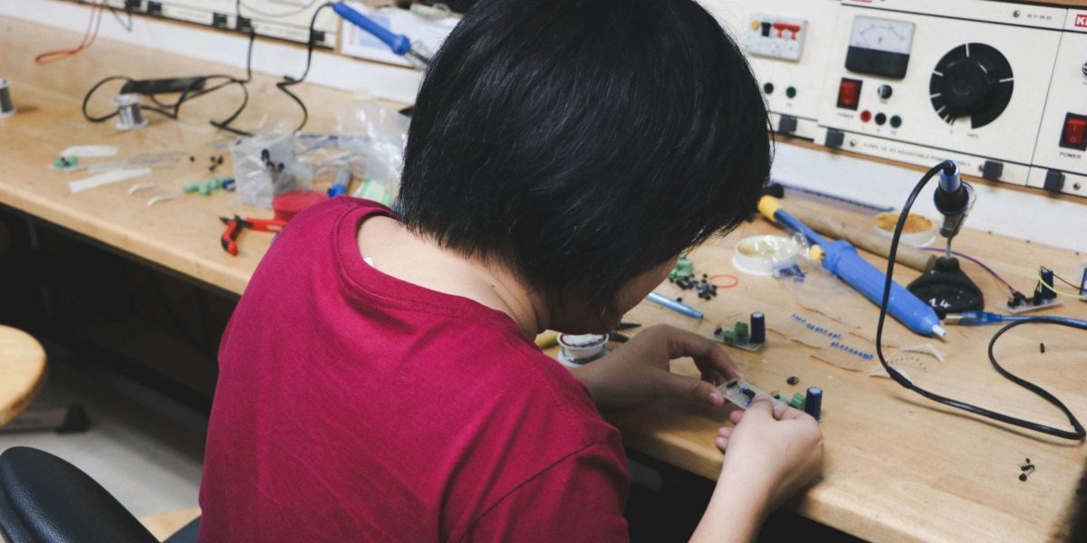 a person working on circuitry with a soldering and other components on a table