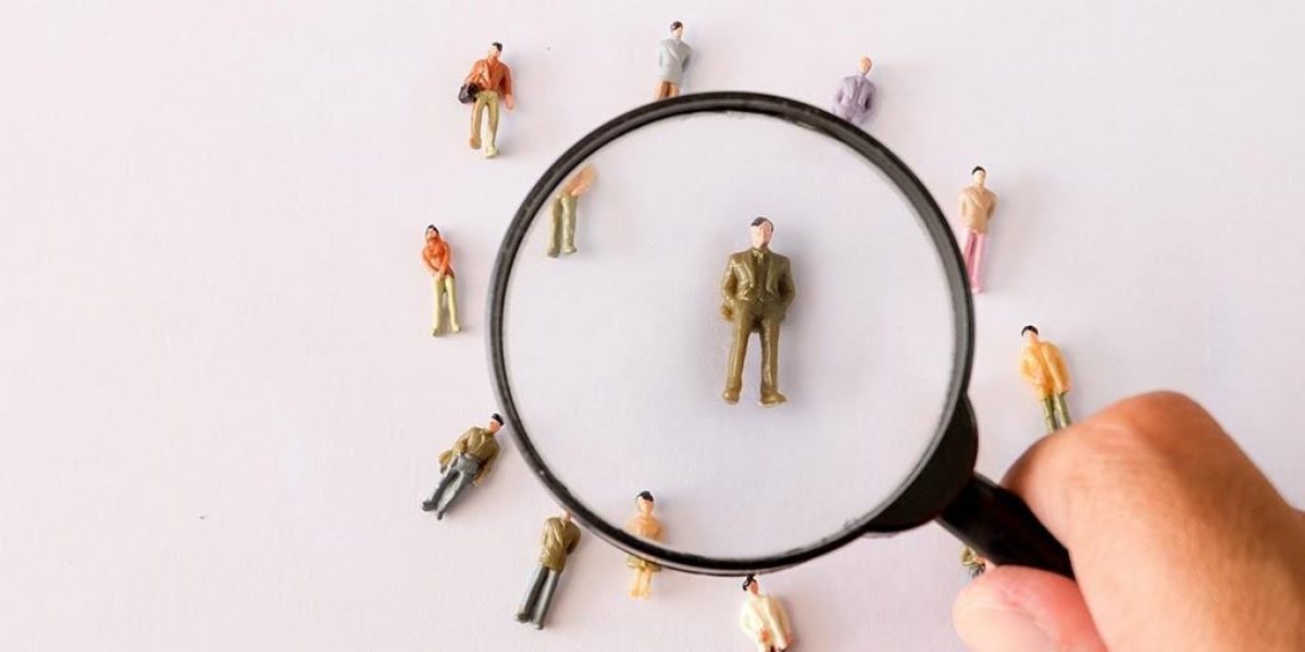 Photo of magnifying glass and tiny toy people against white background
